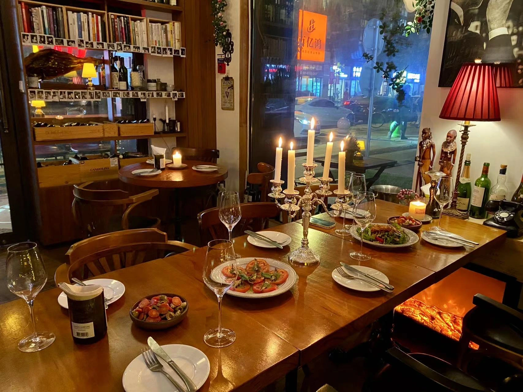 Close detail of candlelight, glasses and shared plates on a wooden table