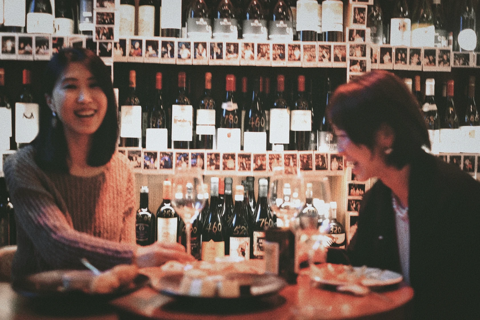 Two guests laughing together over wine at Pure Wine
