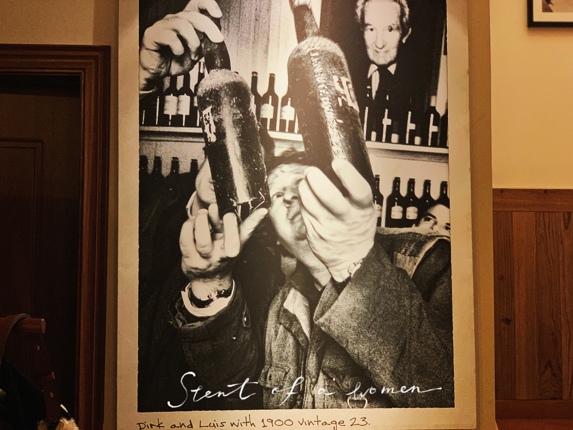 A photograph of wine lovers displayed on the wood-panelled wall at Pure Wine